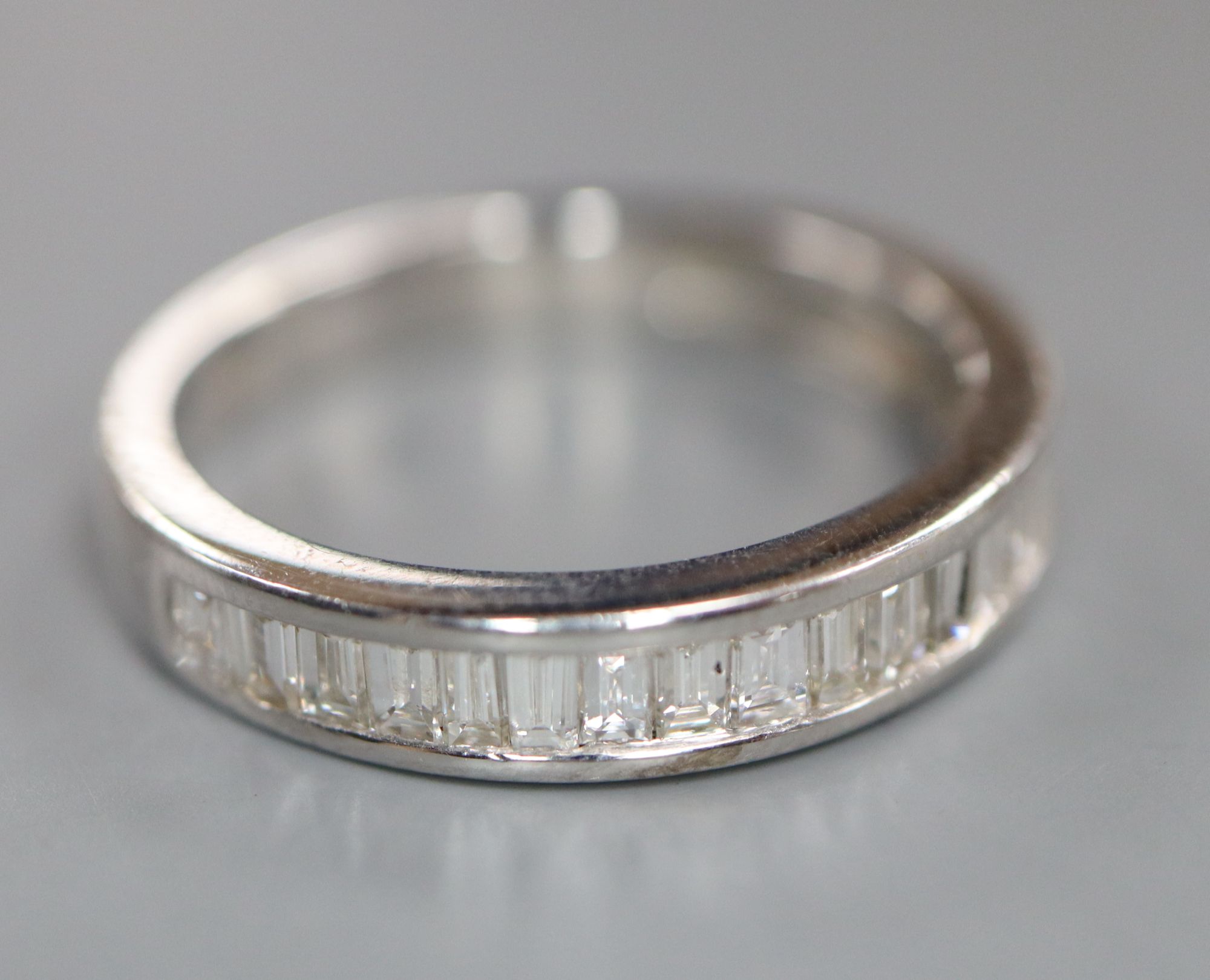 A modern 750 white metal and channel set twenty stone diamond half eternity ring, size O, gross 3.9 grams.